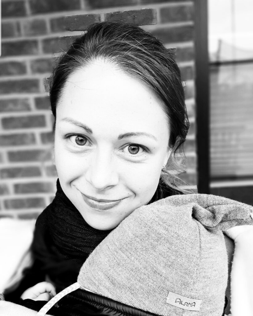 Jasmina Tiedemann hält ihr Baby mit Mütze auf dem Arm