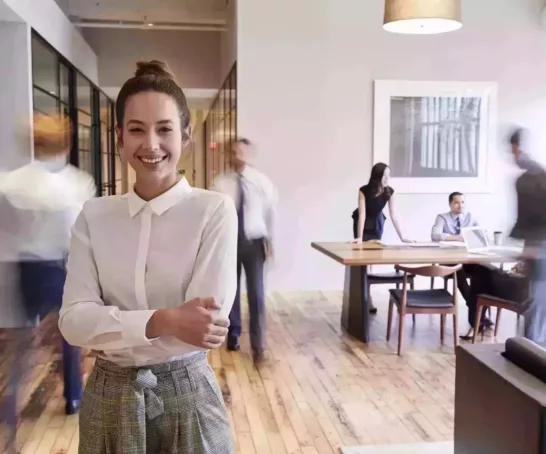 Eine Frau steht in einem Raum mit Menschen im Hintergrund.