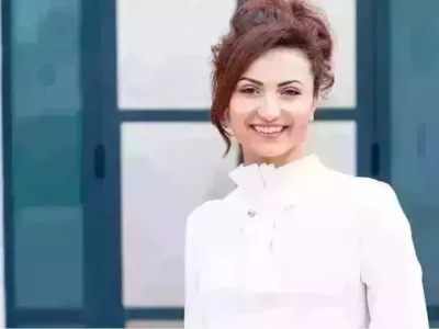 Eine Frau in einem weißen Hemd lächelt in die Kamera.
