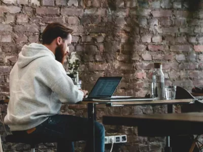 Ein Mann sitzt an einem Tisch und benutzt einen Laptop.