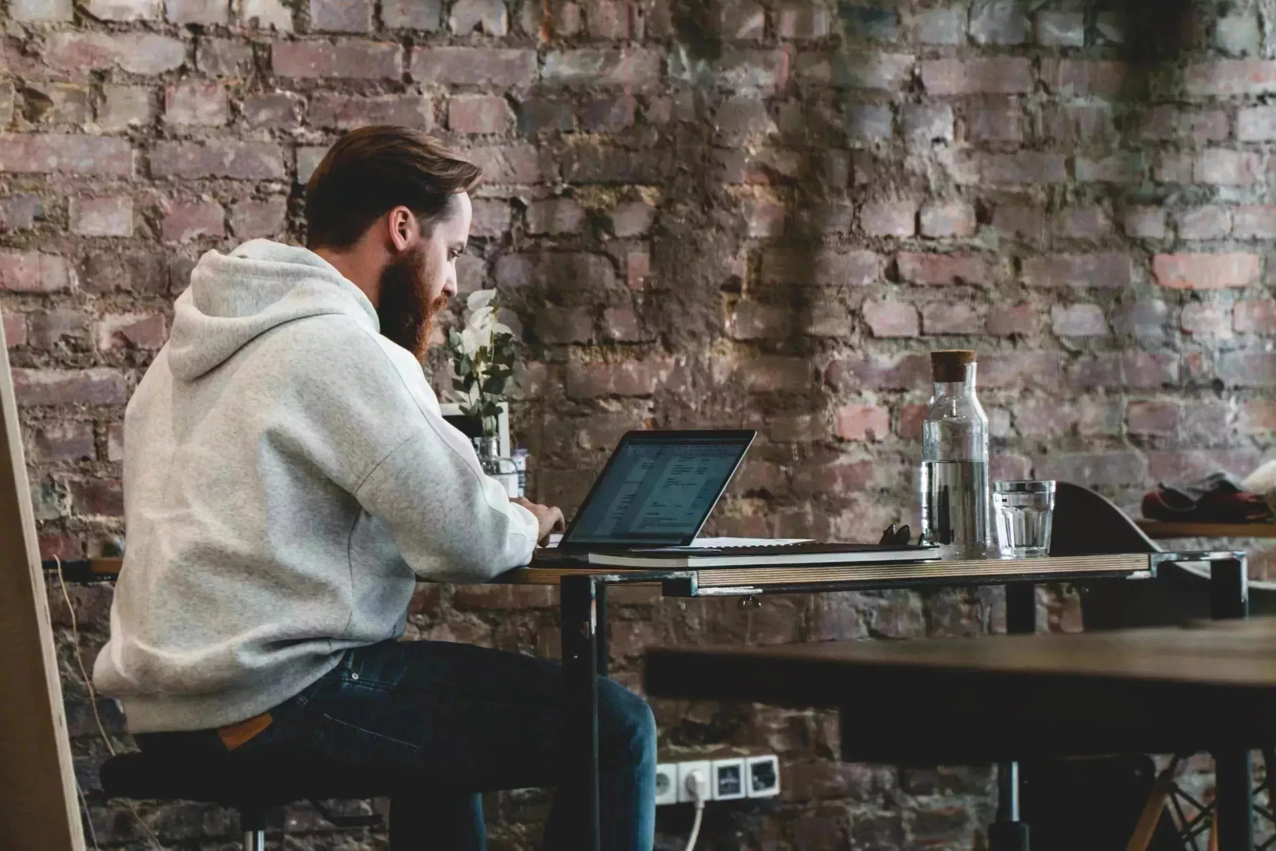 Ein Mann sitzt an einem Tisch und benutzt einen Laptop.