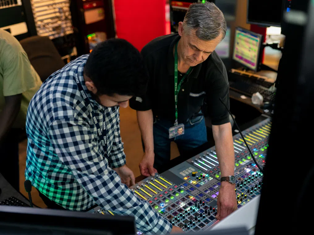 Zwei Männer schauen auf eine Soundkarte in einem Aufnahmestudio.