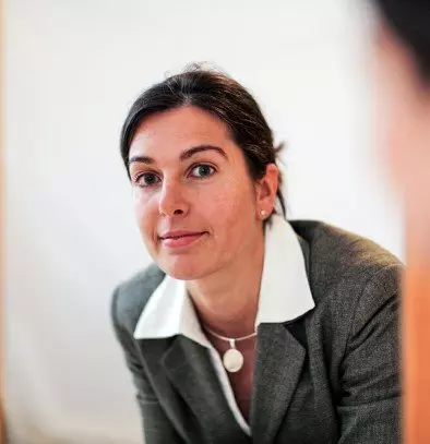 Eine Frau in einem Business-Anzug schaut einen Mann im Anzug an.