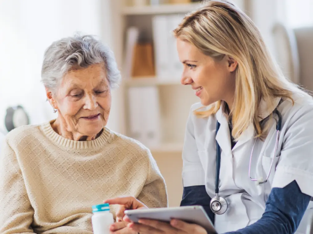 Eine Krankenschwester und ein Patient schauen auf ein Tablet.