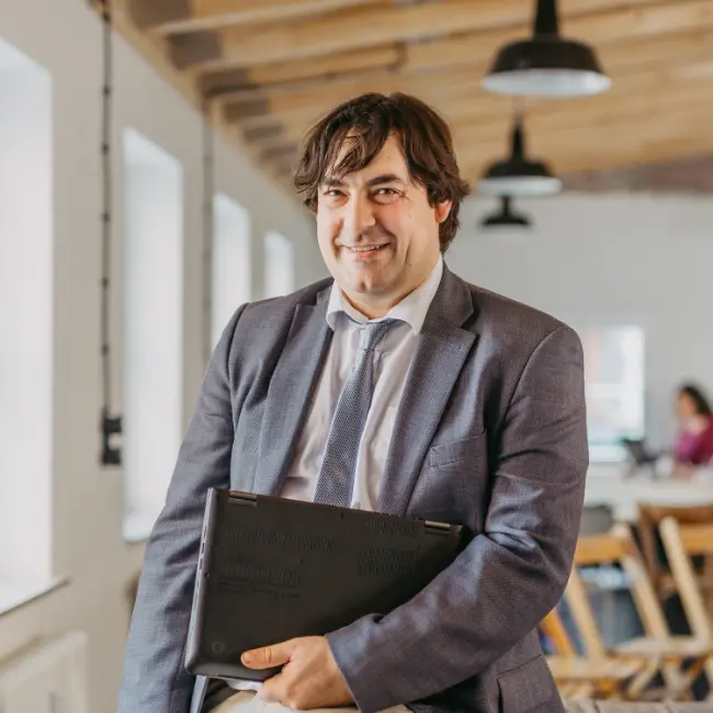 Prof. Dr. Markus Grottke in Anzug und Krawatte hält einen Ordner in der Hand.