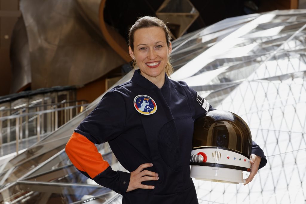 Nicola Baumann, die Astronautin, hält einen Weltraumhelm.