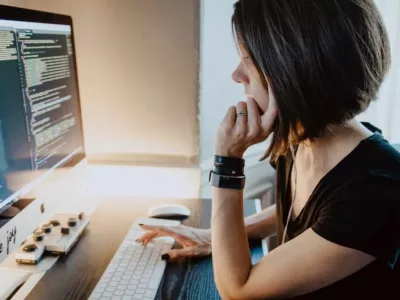 Eine Frau sitzt an einem Schreibtisch vor einem Computer und arbeitet in der Zukunft des Bereichs Wirtschaftsinformatik.