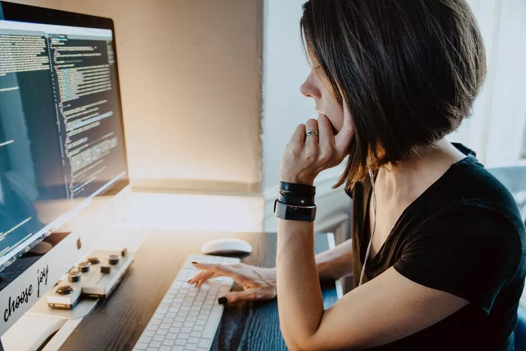 Eine Frau sitzt an einem Schreibtisch vor einem Computer und arbeitet in der Zukunft des Bereichs Wirtschaftsinformatik.