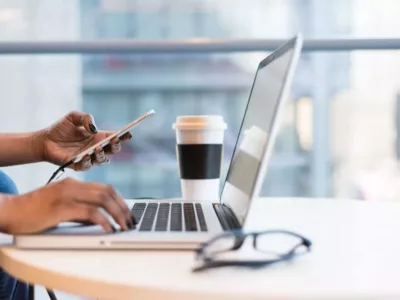 Laptop steht auf Tisch mit Brille und Kaffeebecher