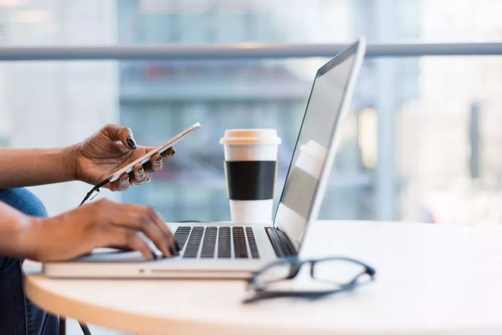 Laptop steht auf Tisch mit Brille und Kaffeebecher