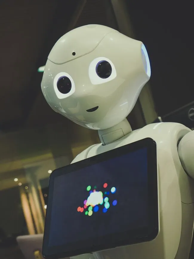 Ein weißer Roboter mit einem Tablet und einem farbenfrohen Bildschirm, die die Zukunft der Menschheit repräsentieren.