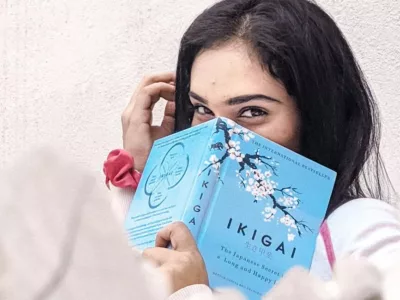 Eine Frau hält ein blaues Buch vor ihr Gesicht