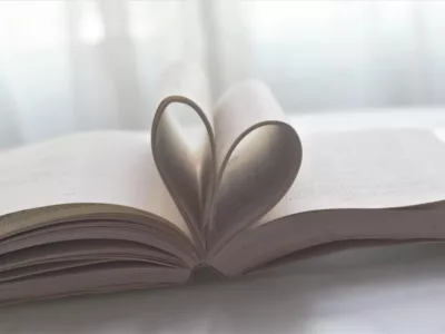 Ein offenes Buch mit einer Liebe-Herzform darauf.