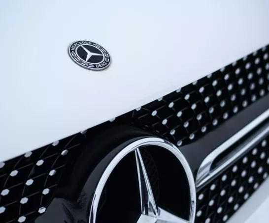 Eine Nahaufnahme eines Mercedes-Logos auf einem Auto.