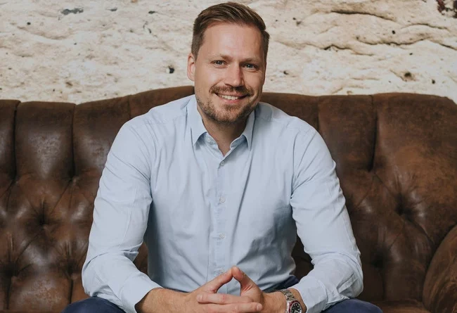 Sebastian Steiger der auf einer braunen Couch sitzt.