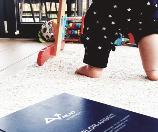 ein Baby, das neben einem Buch auf dem Boden steht.