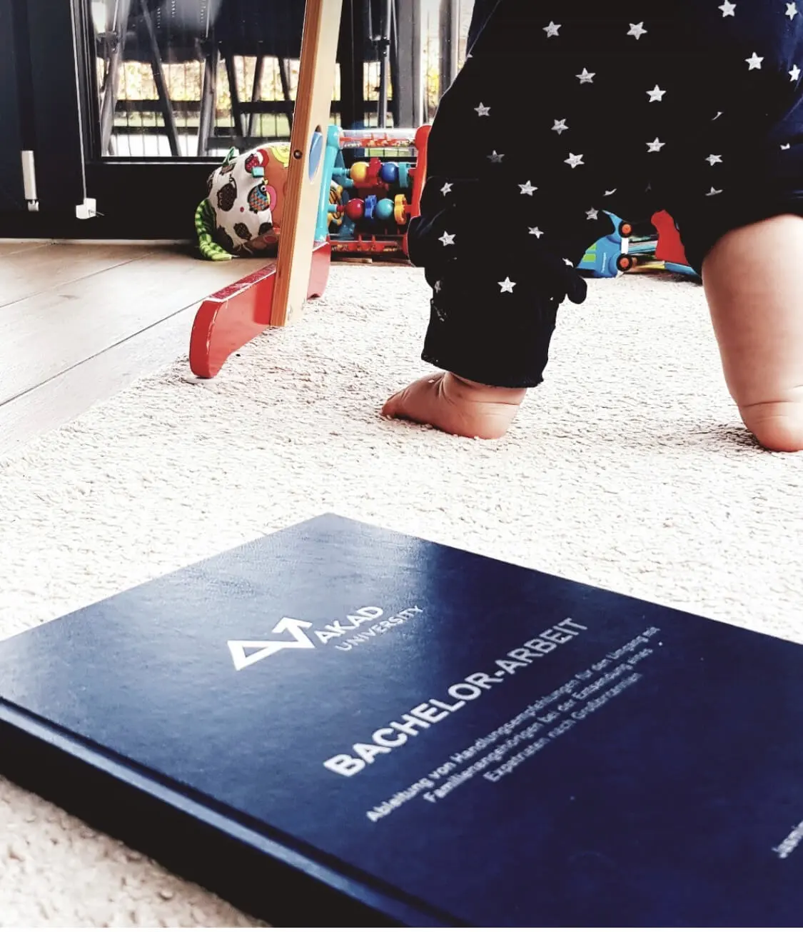 ein Baby, das neben einem Buch auf dem Boden steht.