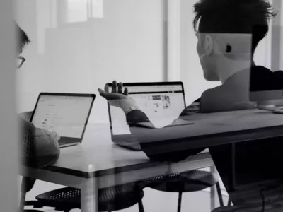 Zwei Studierende arbeiten an einem Tisch am Laptop in einem Meeting