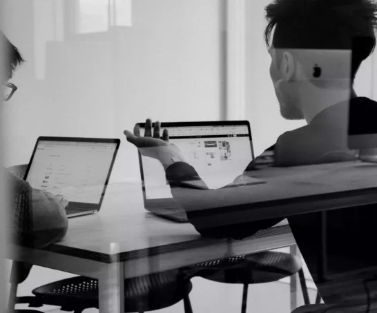 Zwei Studierende arbeiten an einem Tisch am Laptop in einem Meeting