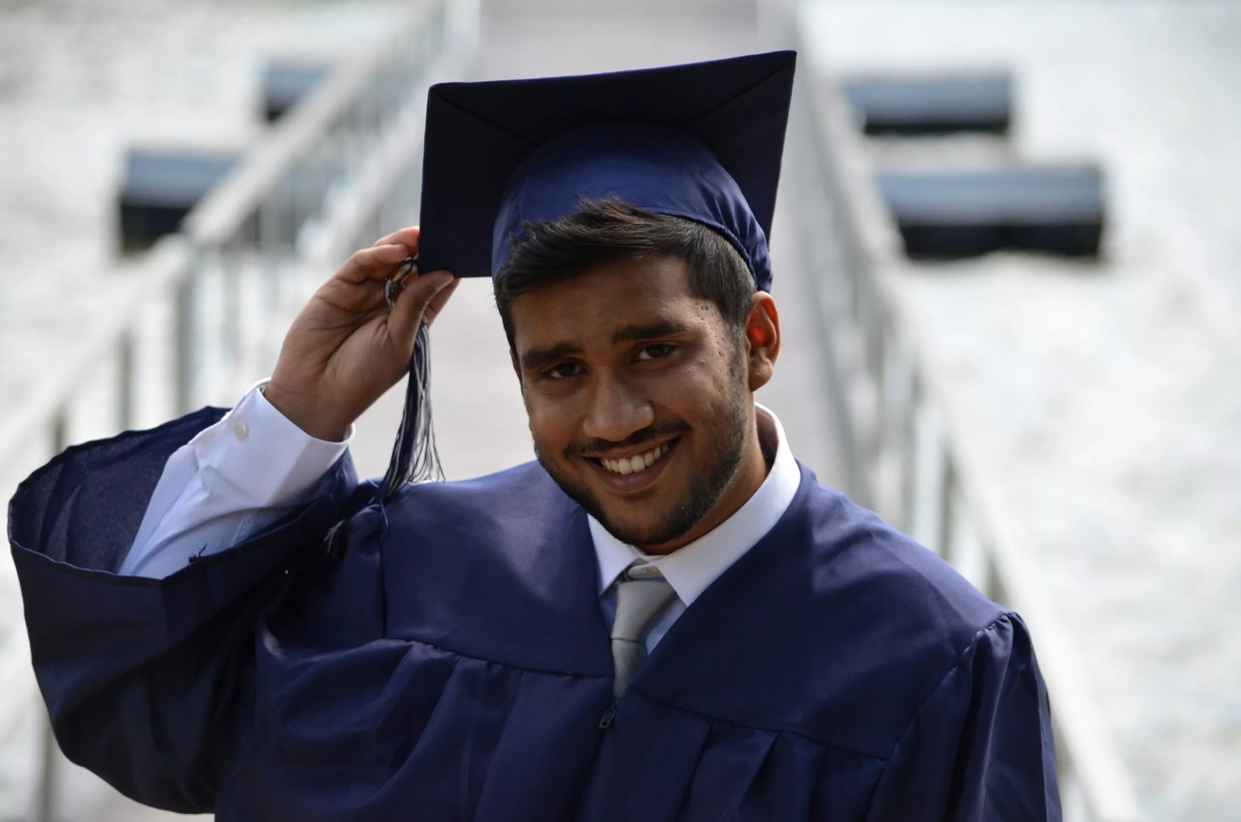 Ein Absolvent in seinem Talar mit Hut lächelt