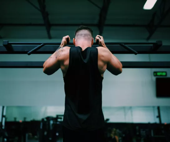 Mann hängt an Klimmzugstange