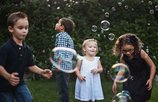 Eine Gruppe Kinder spielt im Hof mit Seifenblasen