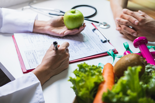 Ernährungsberaterin berät Patientin mit gesundem Obst und Gemüse.