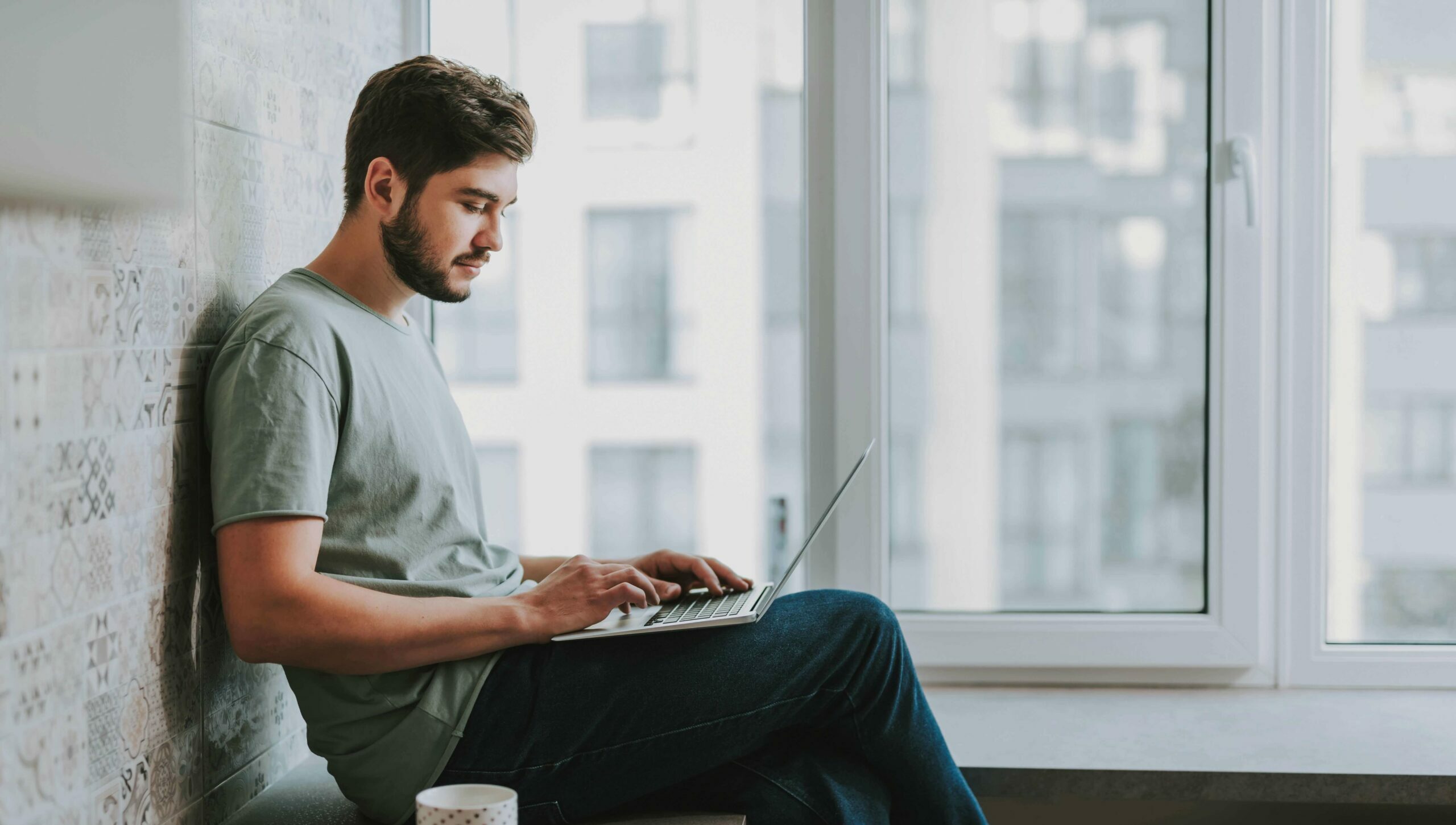 Student sitzt auf einer Bank mit Laptop, Kaffee und Block