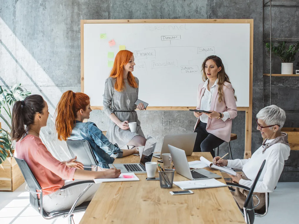 Geschäftsteam bei Besprechung vor Whiteboard mit Organisationsstruktur