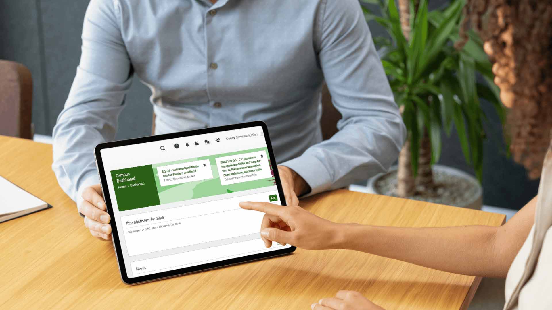 Eine Studentin zeigt auf einem Tablet den AKAD-Campus