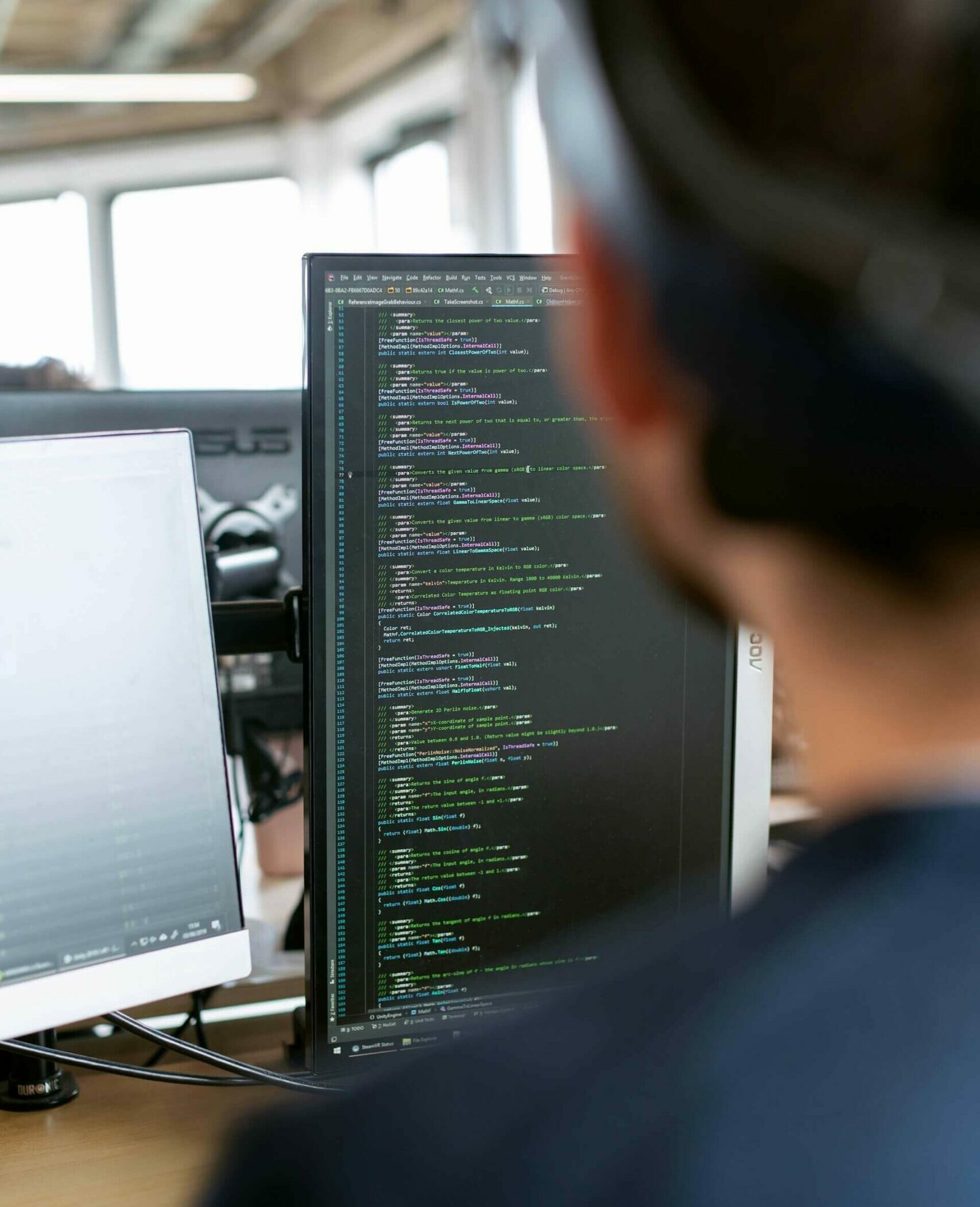 Mann im schwarzen Hemd sitzt vor Computermonitor