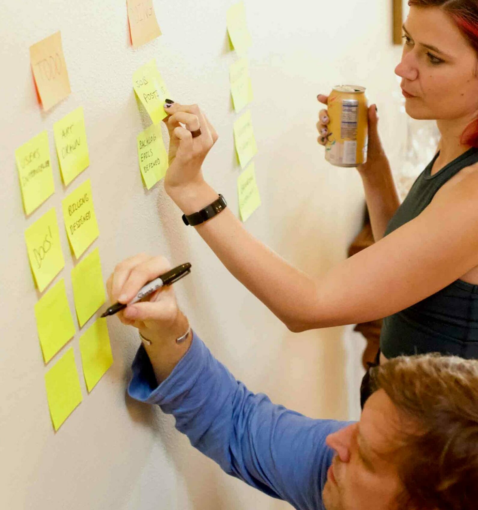 Studentin klebt gelbe Notizblöcke an eine weiße Wand während eines Brainstorming-Meetings