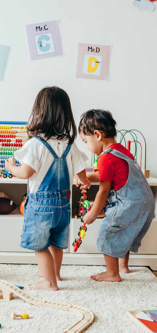 Gruppe von Kleinkindern spielt zusammen mit Holzspielzeug und Lernmaterialien in einem farbenfrohen Klassenzimmer