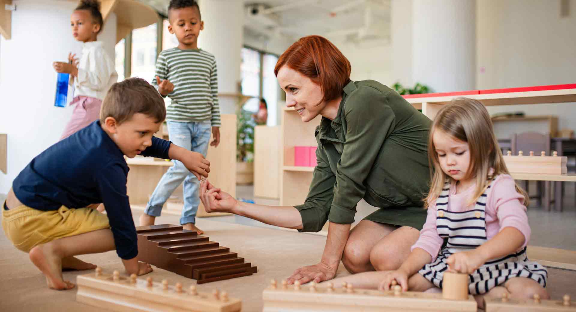 Erzieherin arbeitet mit Kleinkindern an Montessori-Lernmaterialien im Klassenzimmer