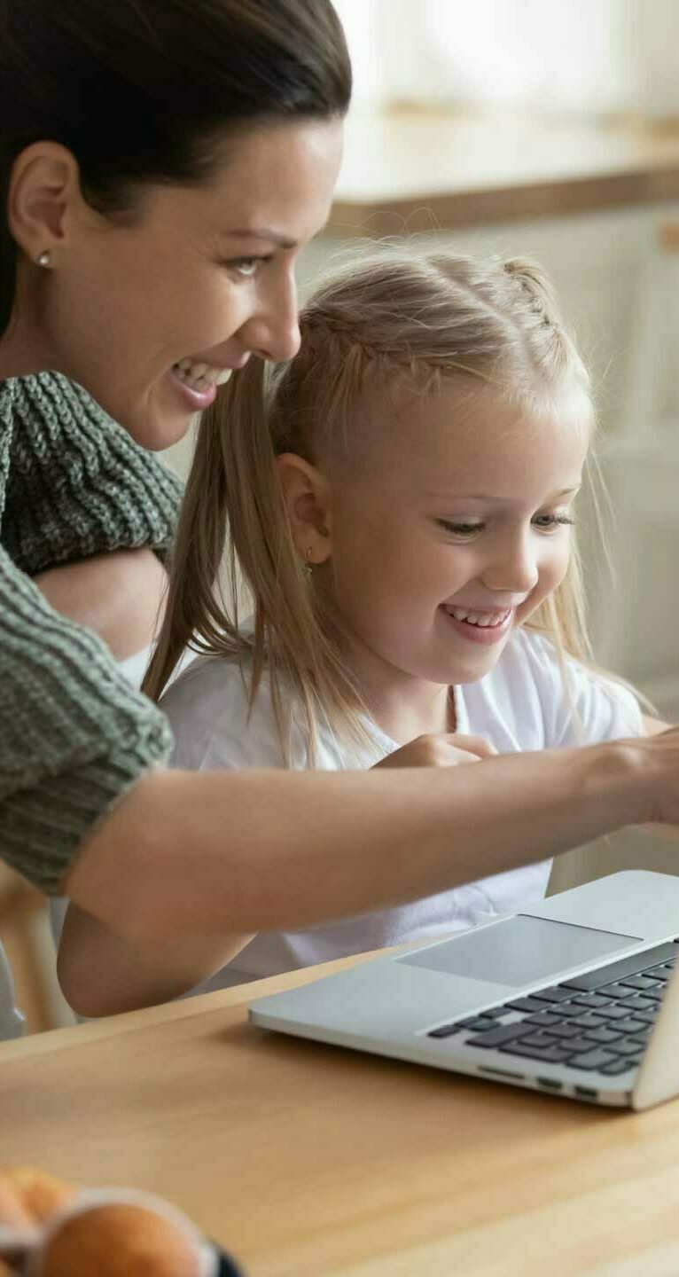 Glückliche Mutter und Tochter nutzen gemeinsam Laptop zu Hause.
