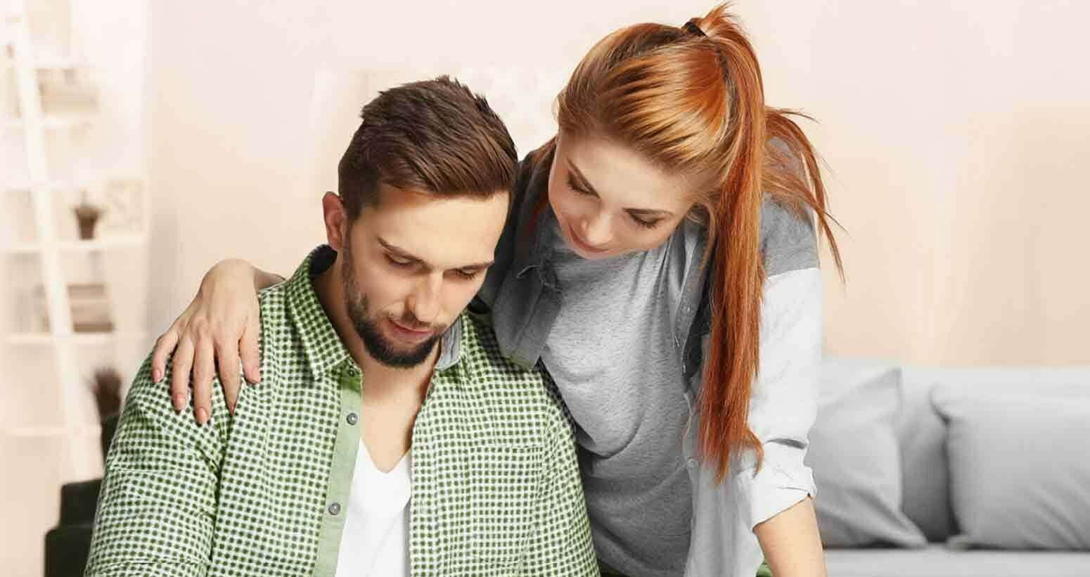 Ein Mann in grünem Hemd und eine rothaarige Frau schauen zusammen auf ein Tablet.