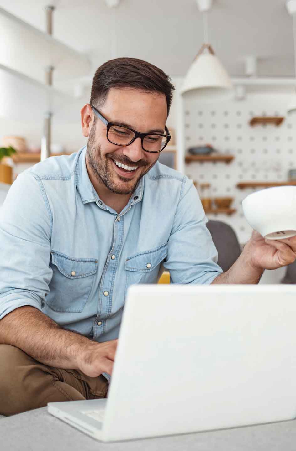 Student mit Brille arbeitet lächelnd am Laptop.