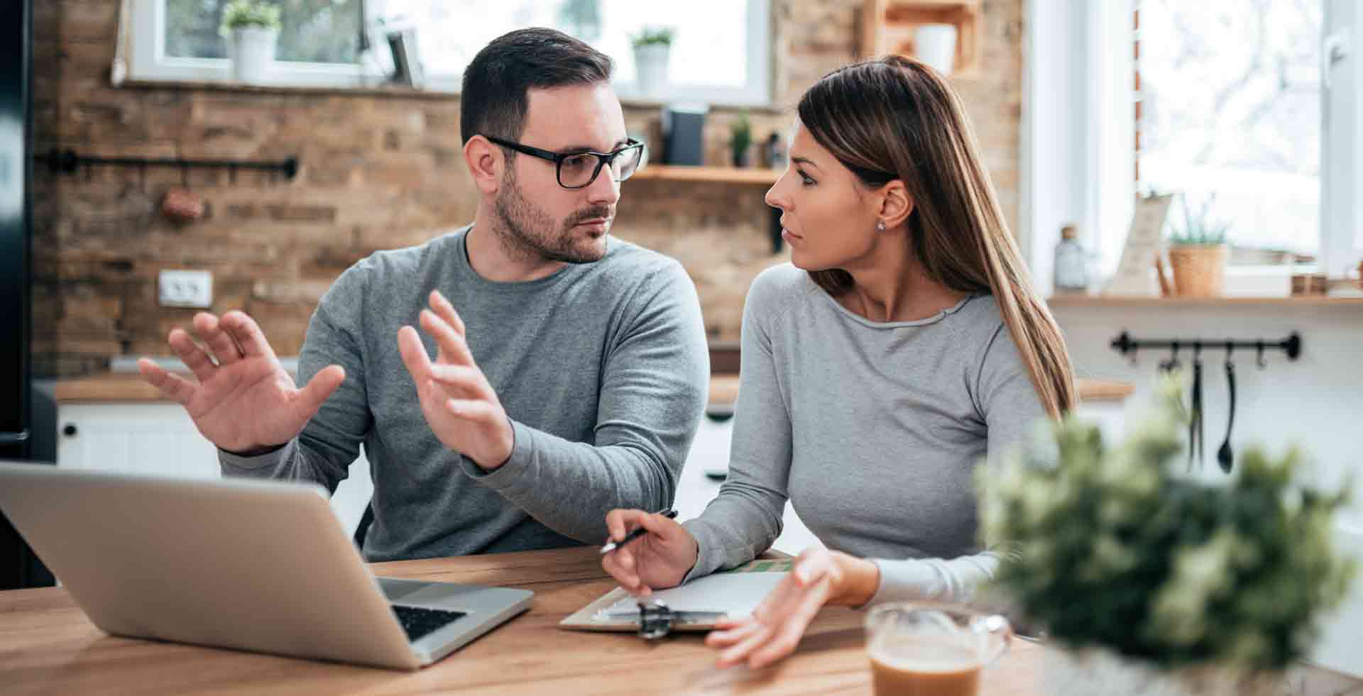 Ein Mann und eine Frau sitzen an einem Laptop und besprechen ein Fernstudium in ihrer Küche